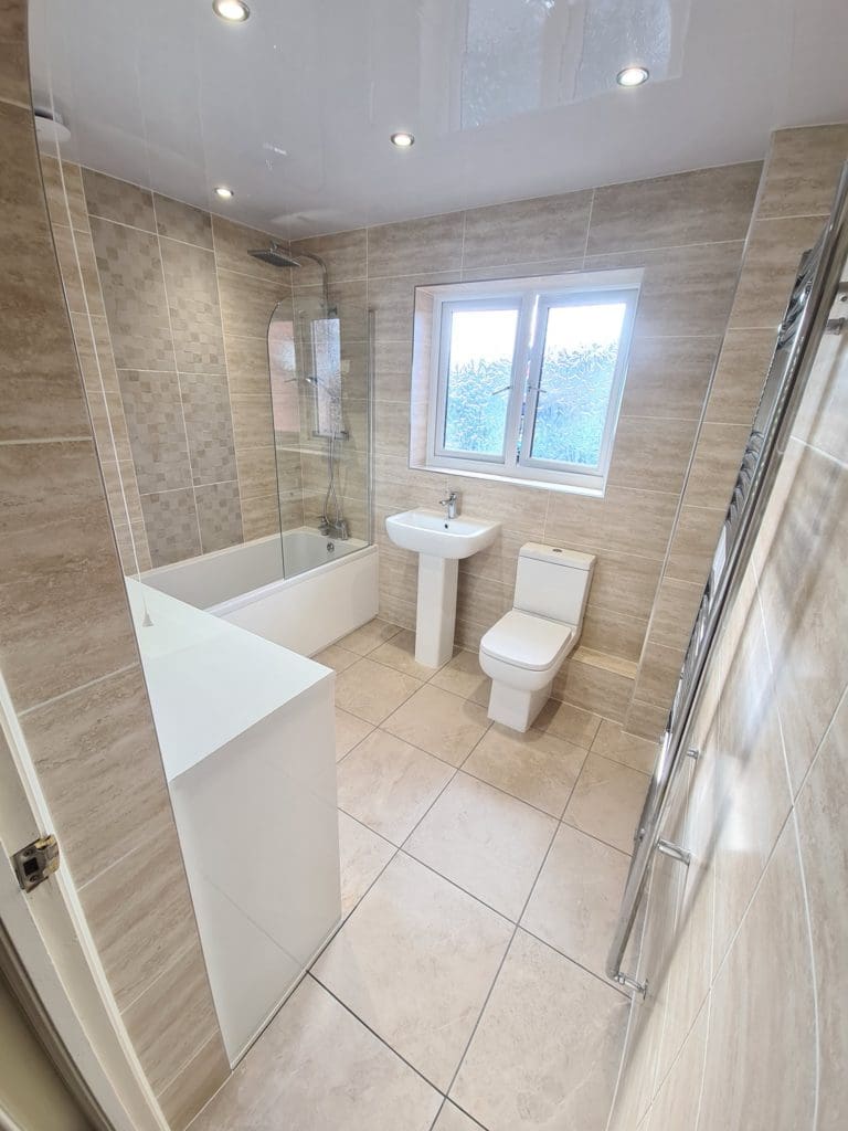 Classic, tiled bathroom with sink, WC bath with a over head shower designed and fitted by Aquarella Bathrooms