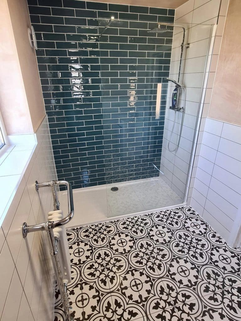 Walk in shower with subway style wall tiles and patterned floor tiles, fitted by Aquarella Bathrooms