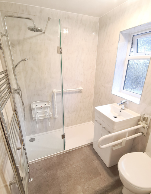 Disabled shower room with shower seat, shower railing and toilet barrier fitted by Aqaurella Bathrooms